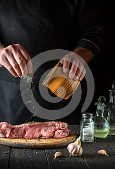 Cook prepares raw veal meat. Before baking, the chef adds a dry herbal seasoning to the beef. National dish is being prepared in