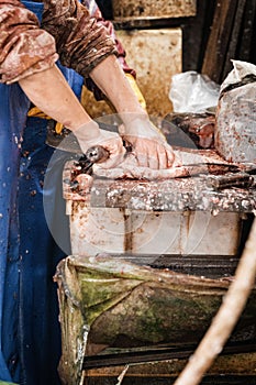 Cook is preparing a meal in the kitchen by filleting a fish with a knife.