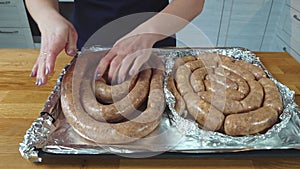 the cook puts the raw sausage on a baking sheet. the process of making homemade grilled sausage from minced meat.