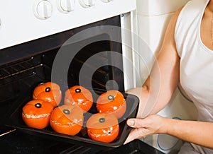 Cook putting farci tomato into oven