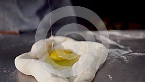 The cook Ñracking a farm fresh egg. the egg is poured on the dough.