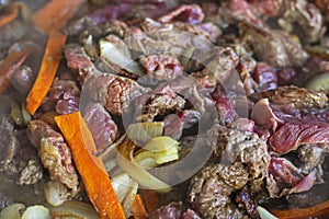 cook raw fresh meat cut into pieces in a frying pan with vegetables,