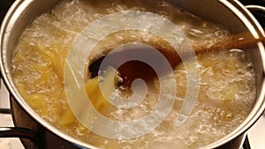 Cook removes the lid from the pot with the pasta in boiling water