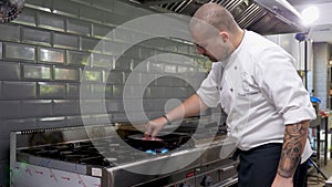 Cook in restaurant kitchen frying meat on stove on a pan
