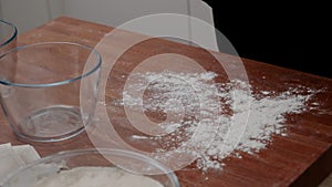 The cook\'s hands sprinkle flour on the table before shaping and placing the dough into the mold. the cook kneads the dough