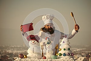 Cook shouting, snowmen and snow xmas tree on blue sky