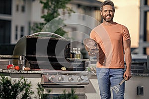 cook showcasing his barbecue techniques at cookout event. Man enjoying barbecuing. man grilling his favorite meats, copy photo