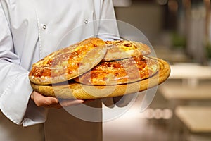 The cook shows a pitas on a wooden board