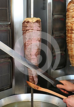 Cook Slicing Turkish Lamb Doner Kebab with a Sharp Sword like Knife