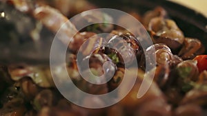 Cook stirring a pot of cooking snails