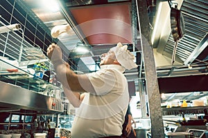 Cook tossing dough while preparing pizza in a modern Italian restaurant