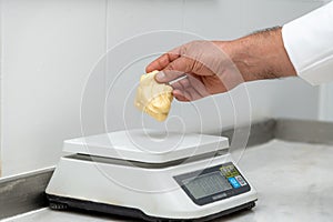 Cook weighing hamburger bun dough on scale on marble counter