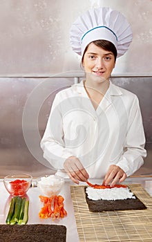 Cook woman making sushi rolls