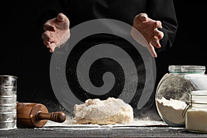 The cook works, makes the dough, kneads it in his hands on a black background. Freezing in motion. Cooking baking, culinary