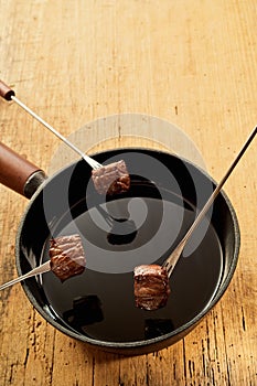 Cooked Beef on Fondue Forks with Pot of Hot Oil