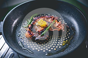 Cooked beef steak with rosemary and garlic inside iron skillet