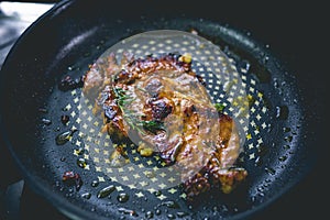 Cooked beef steak with rosemary and garlic inside iron skillet