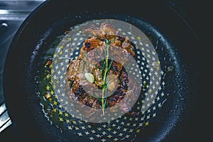 Cooked beef steak with rosemary and garlic inside iron skillet