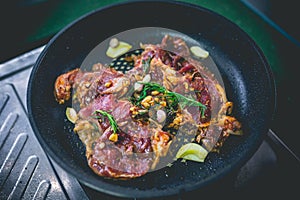 Cooked beef steak with rosemary and garlic inside iron skillet