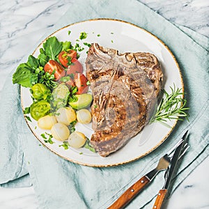 Cooked beef tbone steak with vegetables and rosemary, square crop photo