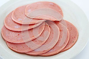 Cooked boiled ham sausage or rolled bologna slices on a white plate