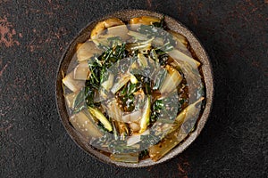 Cooked bok choy or chinese cabbage with sesame seeds and soy sauce on dark background. Asian chinese food. top view