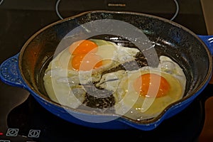 A cooked breakfast has the surprise of a double-yolked egg, breakfast being cooked in a cast iron pan
