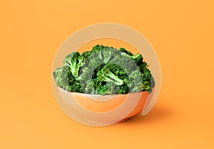Cooked broccoli in a bowl isolated on an orange background