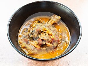 Cooked Chakhokhbili in black bowl on pink board