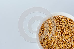 Cooked chick peas in a white ceramic bowl isolated on white. Spilled chick peas. Top view