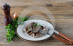 Cooked chicken liver with onion on a plate served on wooden desk. Rustic style