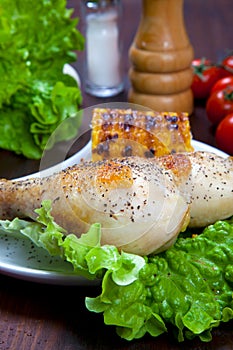 Cooked chicken thigh with a boundary of corn cob and salad