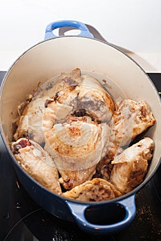 Cooked chicken thighs in a blue casserole dish