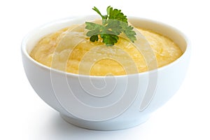 Cooked cornmeal polenta with green parsley in white ceramic bowl