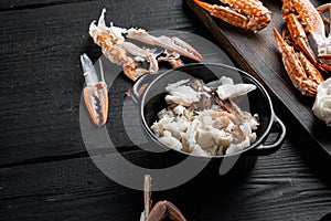 Cooked crab claws and legs meat, on black wooden table background