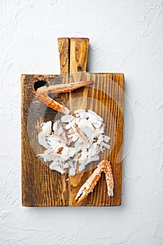 Cooked crab claws and legs meat, on wooden cutting board, on white background, top view flat lay