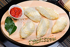 Cooked dumplings mantas on a wooden board on black background