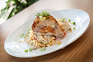 Cooked food in a restaurant on a white plate - tuna served on vegetable risotto.
