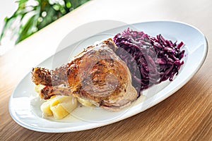 Cooked food - roasted duck leg, red cabbage, potato dumplings.