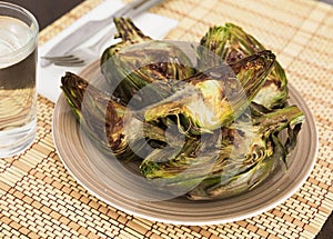 cooked fried halves artichokes on brown plate