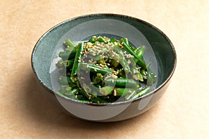 Cooked green beans in a plate on a brown background