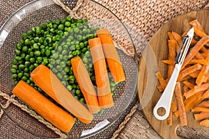 Cooked green peas with cooked carrot on the wooden board