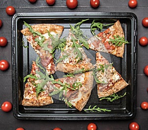 Cooked home meat pizza with rocket salad and cherry tomatoes, on a white rustic background, space for text