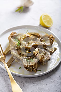 Cooked Italian Artichokes on the white plate with lemon