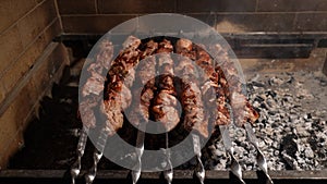 Cooked juicy steak meat beef brushed with rosemary on a flaming grill surrounded by other meat and sausages. slow motion