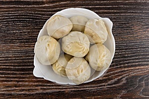 Cooked khinkali in glass bowl on dark wooden table. Top view