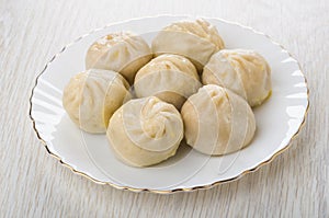 Cooked khinkali in plate on light wooden table