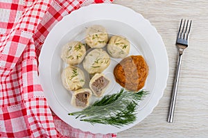 Cooked khinkali, squash caviar, dill in plate, fork, napkin on wooden table. Top view