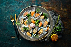 Cooked large green mussels with garlic, parsley and lemon on a metal tray. Seafood.