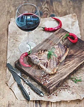 Cooked meat t-bone steak on serving board with roasted tomatoes